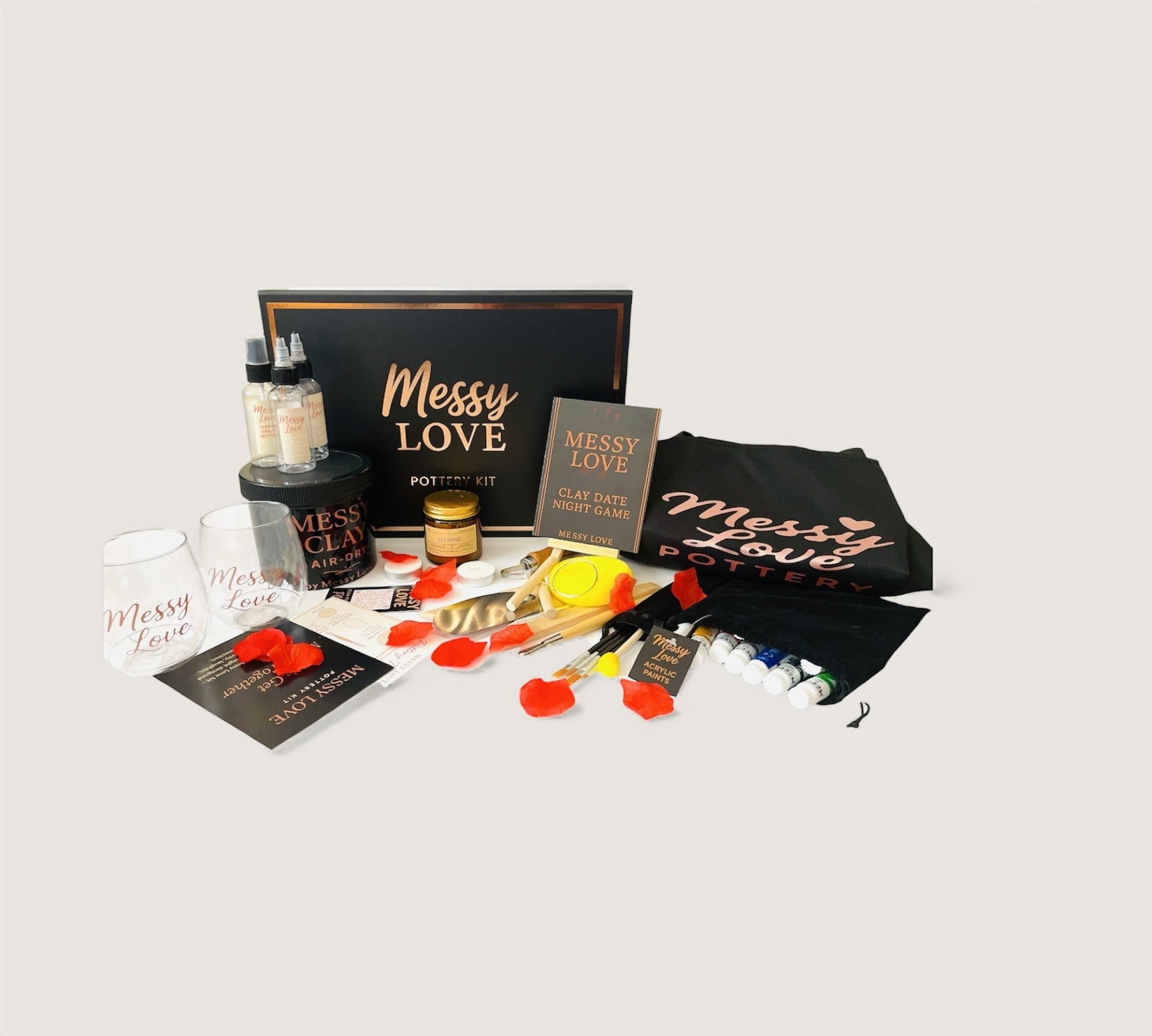 Collection of 'Messy Love' products including a black t-shirt, candles, and other items on a light gray background.